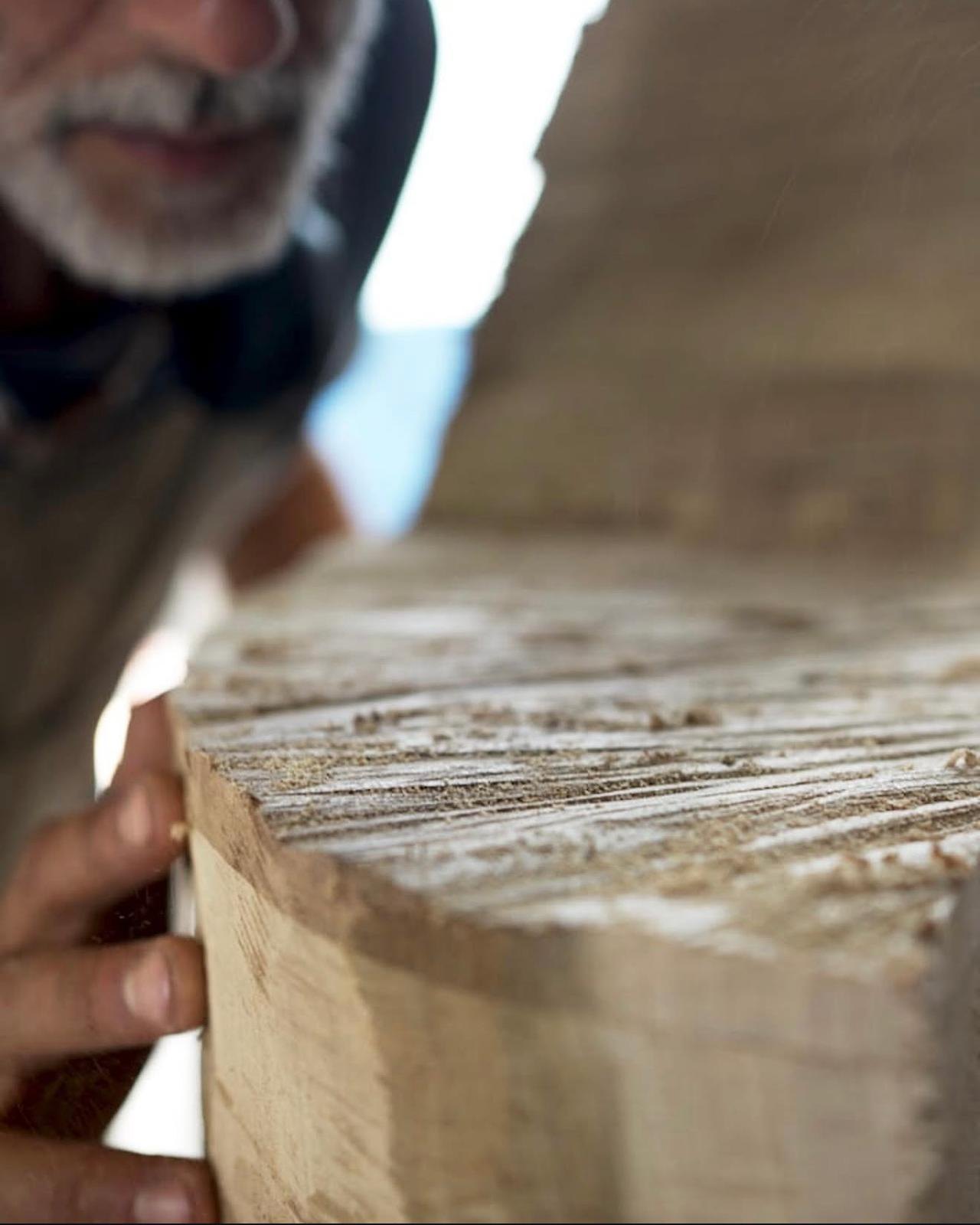 Gianmarco checking a block of wood as he shapes it by hand